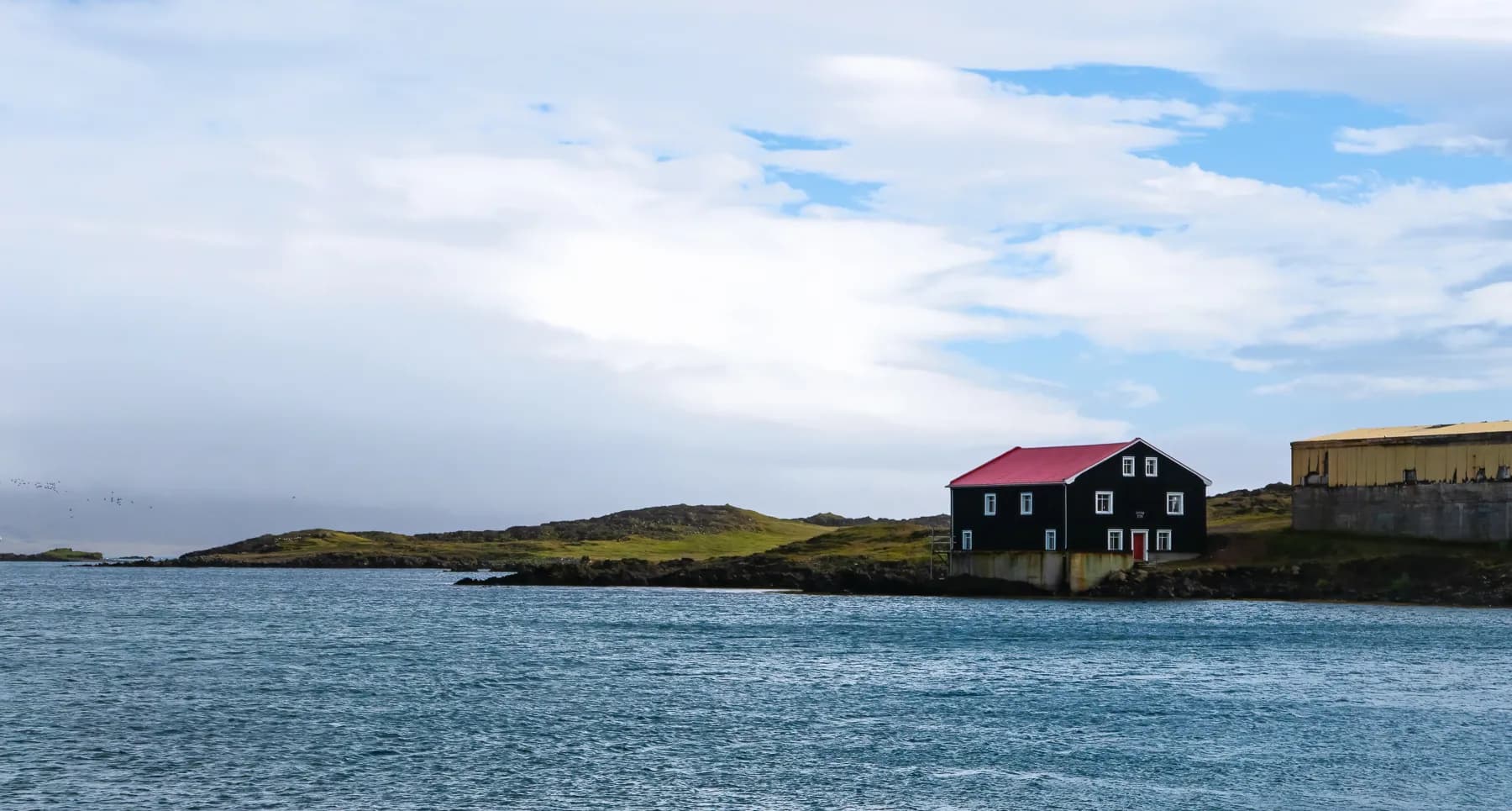 Djúpivogur shoreline view with brown building and red roof