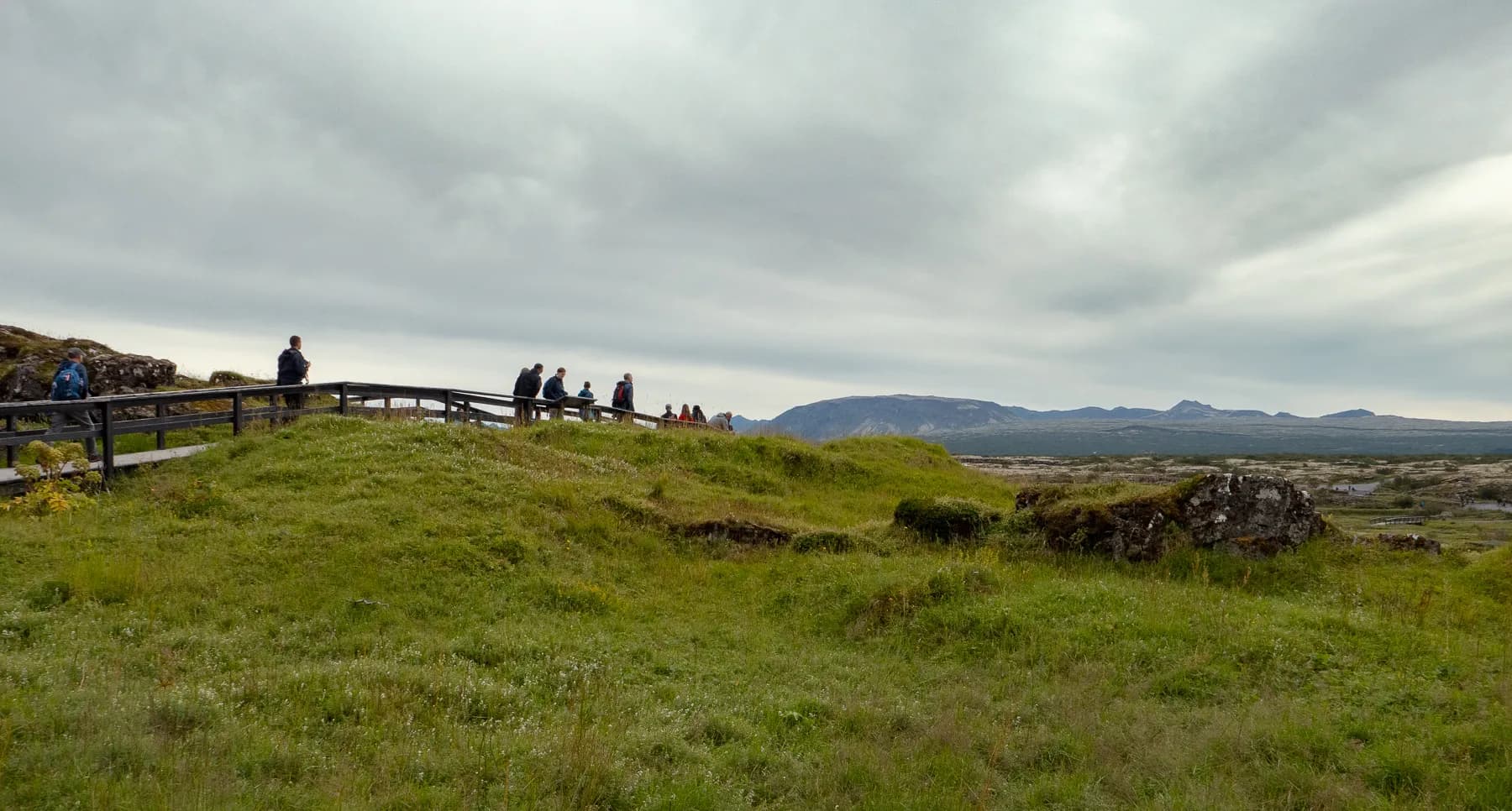 Rolling green landscape under a cloudy sky in Þingvellir National Park, Iceland.