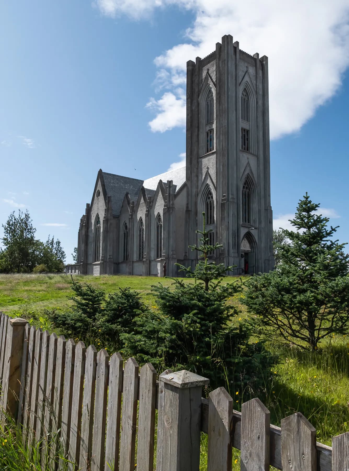 Hallgrímskirkja church rising above greenery and a wooden fence in Reykjavik, Iceland.