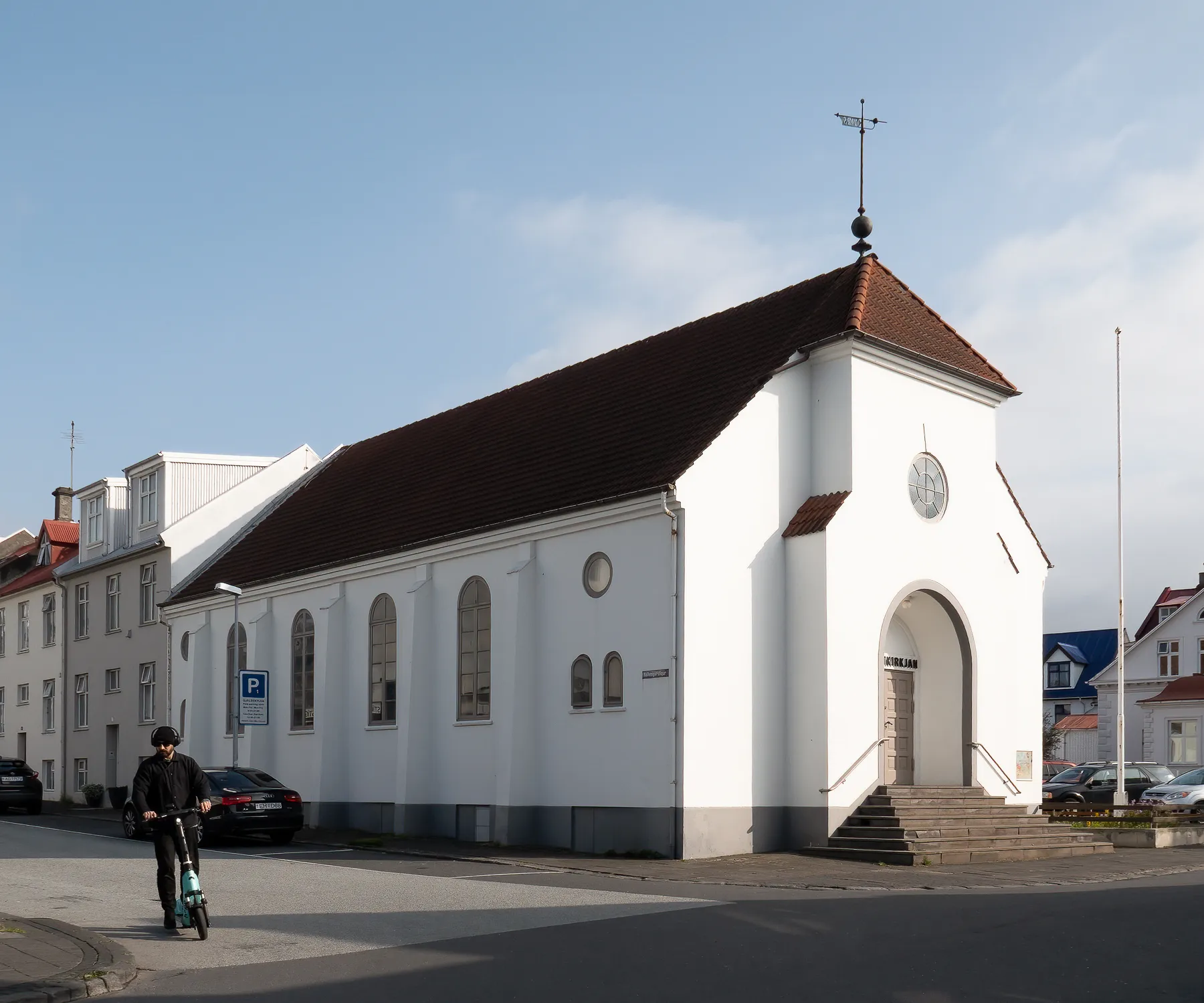 White church with a red roof on a street corner in Reykjavik, Iceland.