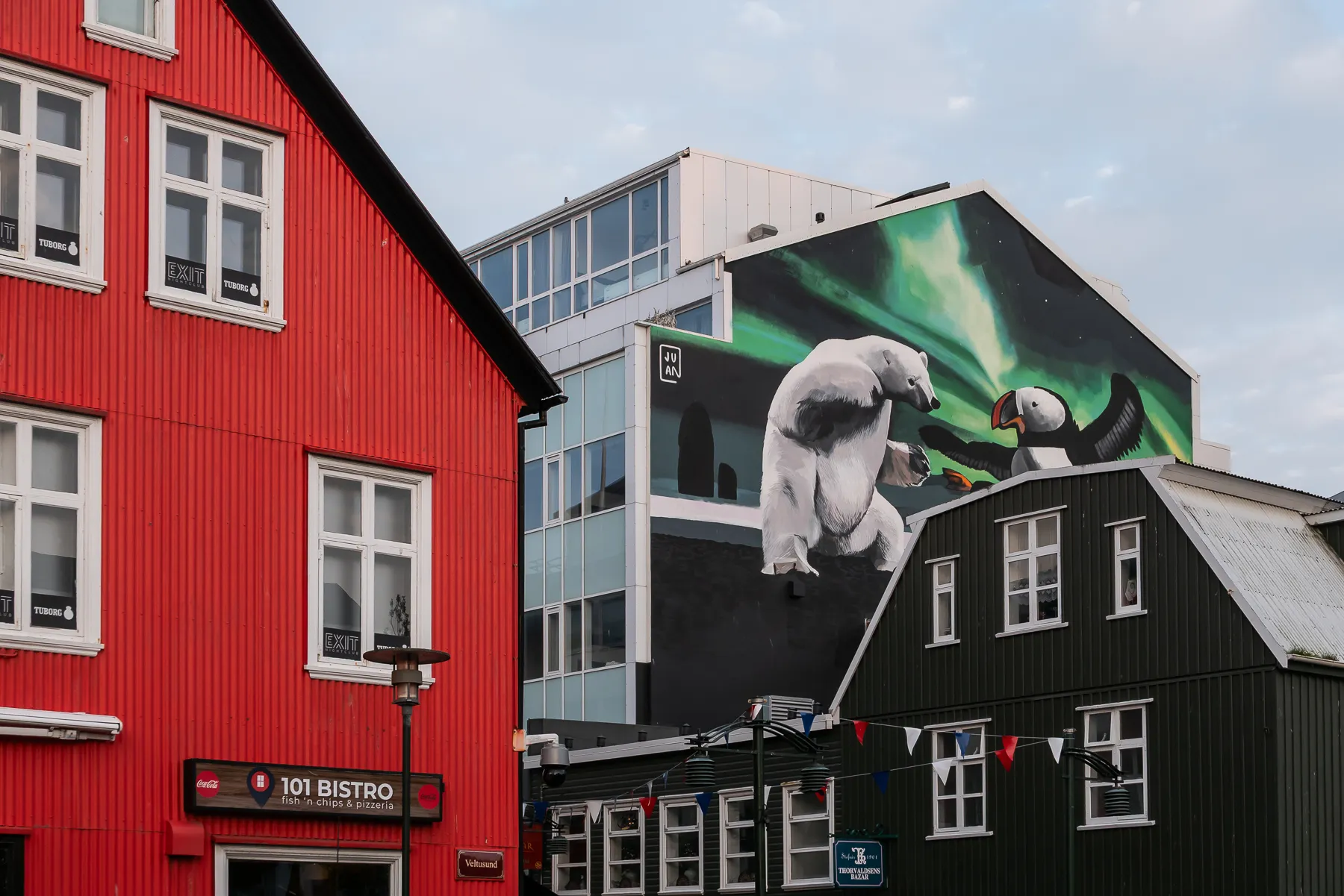 Colorful buildings in Reykjavik, including a red facade and a large mural on a green building.